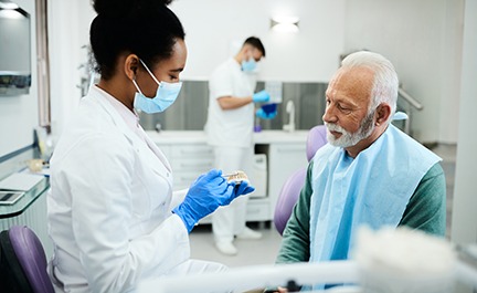 A dentist showing dentures to her senior patient