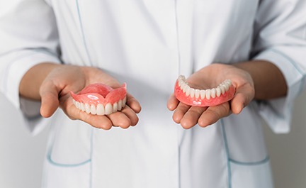 A dentist holding two different dentures in his hands