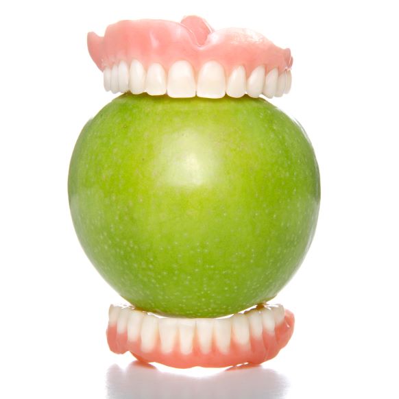 A pair of dentures with an apple in between them